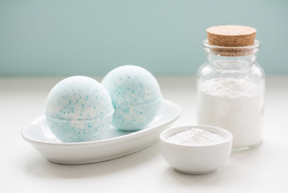Two pale blue bath bombs beside bowls of cream of tartar and cornstarch