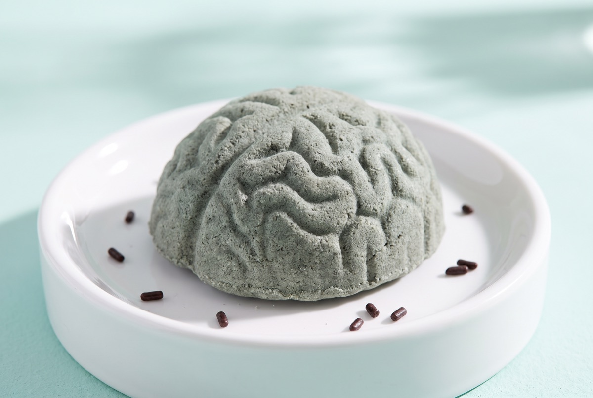 A grey green brain shaped bath bomb on a white dish